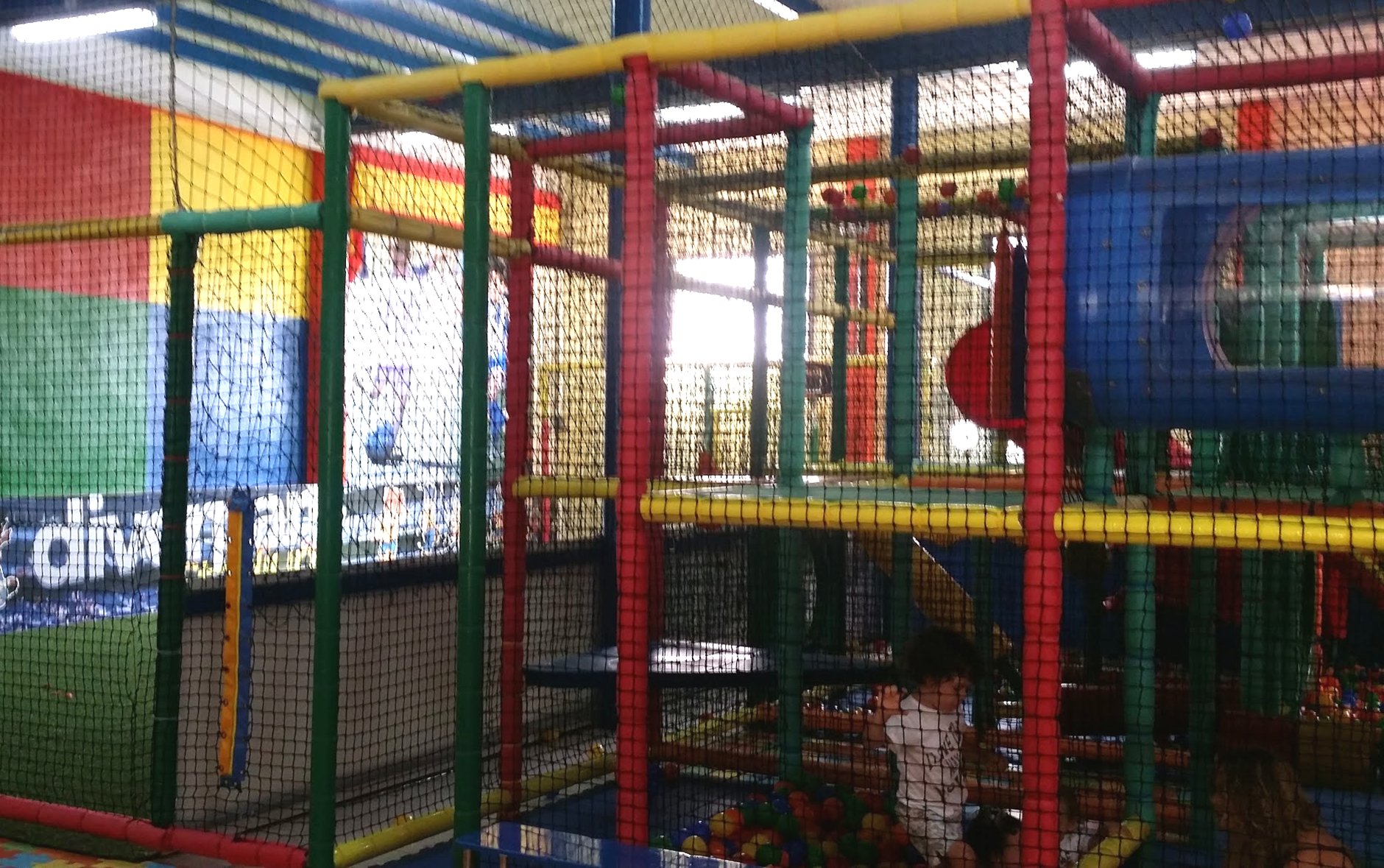 Interior del parque de ocio infantil diverpark en Águilas: estructura de juego de varias alturas con redes y, al fondo, el campo de fútbol cerrado